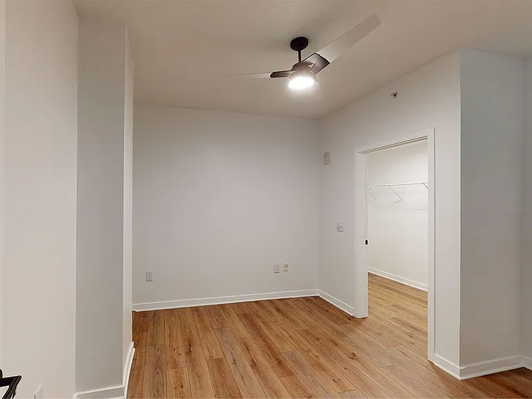 Spacious apartment bedroom with large closet and wood-style flooring.