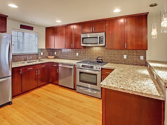 Large kitchen with granite counters, stainless appliances, bamboo hardwood floors and tile backsplash. Breakfast bar for casual dining or morning coffee.