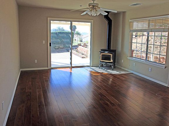 The living room features a wood burning stove, ceiling fan and hardwood floors.
