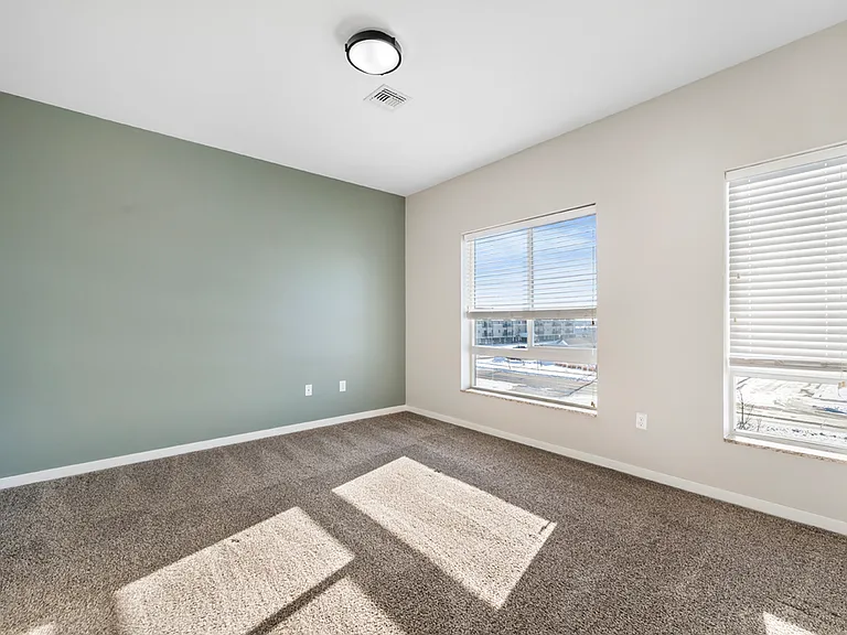 Bright and spacious empty room with soft carpet flooring, large windows, and modern light fixture, ideal for a cozy bedroom or home office. Bright and spacious empty room with soft carpet flooring, large windows, and modern light fixture, ideal for a cozy