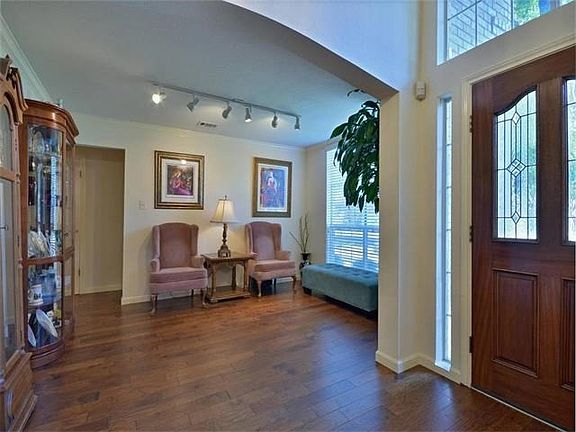The formal living area is adjacent to the foyer has an arched entry opening, hand carved engineered wood flooring, window blinds amd enough wall space for various furniture arrangements.