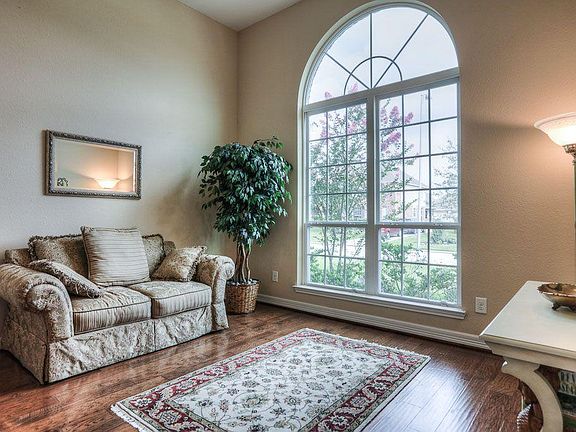 Formal living room with decorative windows to let the natural light in and beautiful wood flooring.