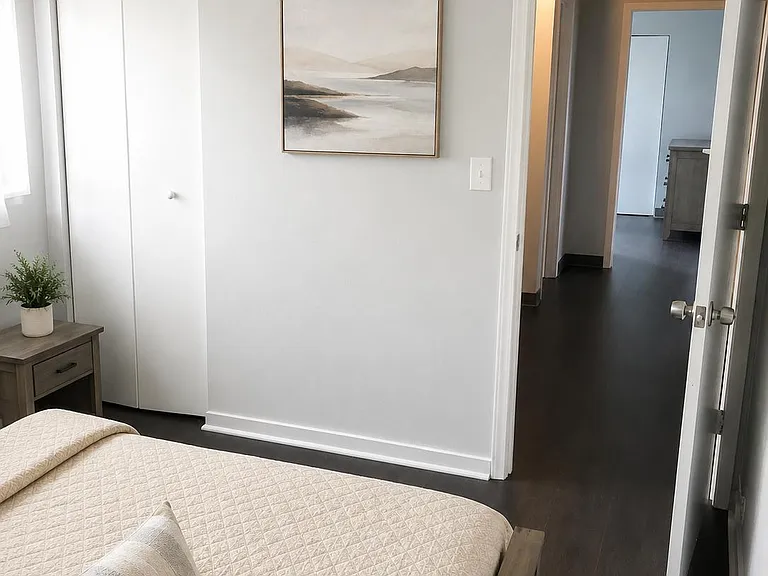 Well-kept bedroom with a comfortable bed setup, bedside table, and a spacious closet, plus easy access to the hallway.