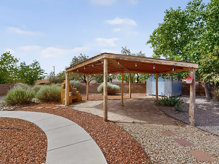 A back yard for entertaining including a large covered southwestern style patio plus a bonus storage shed.