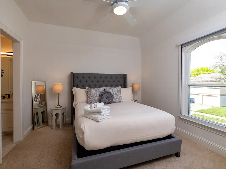 Charming guest room with queen bed and arched window.