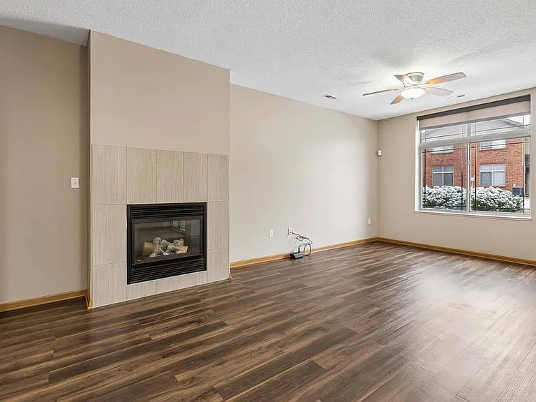 A warm, expansive living room anchored by a cozy fireplace and filled with natural light.