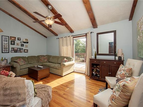 Spacious living room area featuring vaulted beamed ceilings, beautiful hardwood flooring & sliding glass doors tohuge deck.