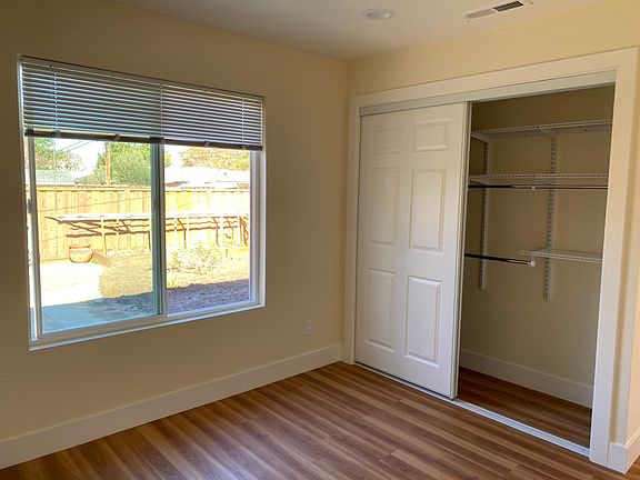 2nd bedroom with closet that has built-in shelves and looks into the backyard