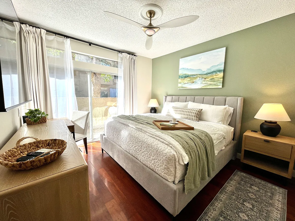 Primary Ensuite with plush king bed and luxe furnishings. Features a mirrored walk-in closet plus extra mirrored closet, 65" Smart TV, and a fully equipped workstation perfect for relaxing, working remotely, or unwinding after a day of exploring. - 25845 McBean Pkwy #17