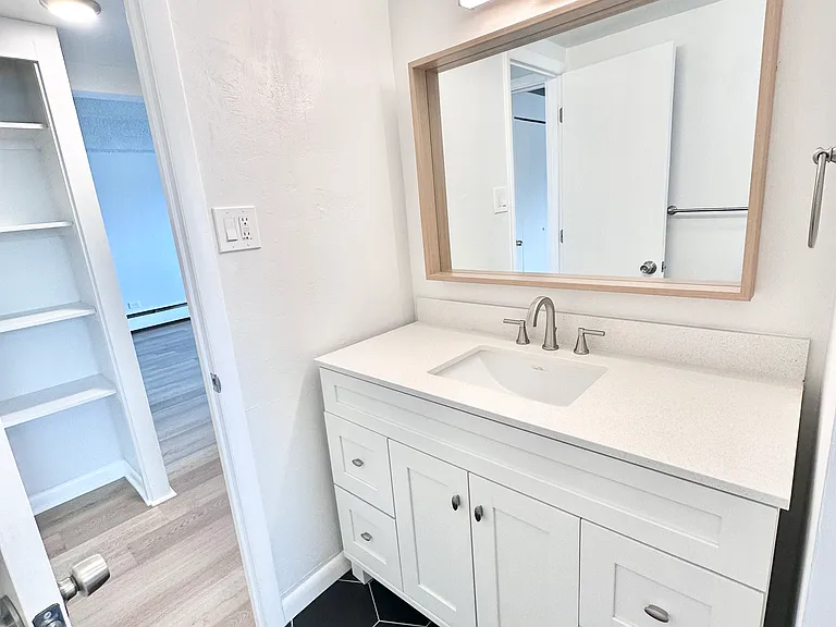 Modern bathroom featuring a sleek white vanity with ample storage, large mirror, and elegant black hexagon floor tiles. Modern bathroom featuring a sleek white vanity with ample storage, large mirror, and elegant black hexagon floor tiles.