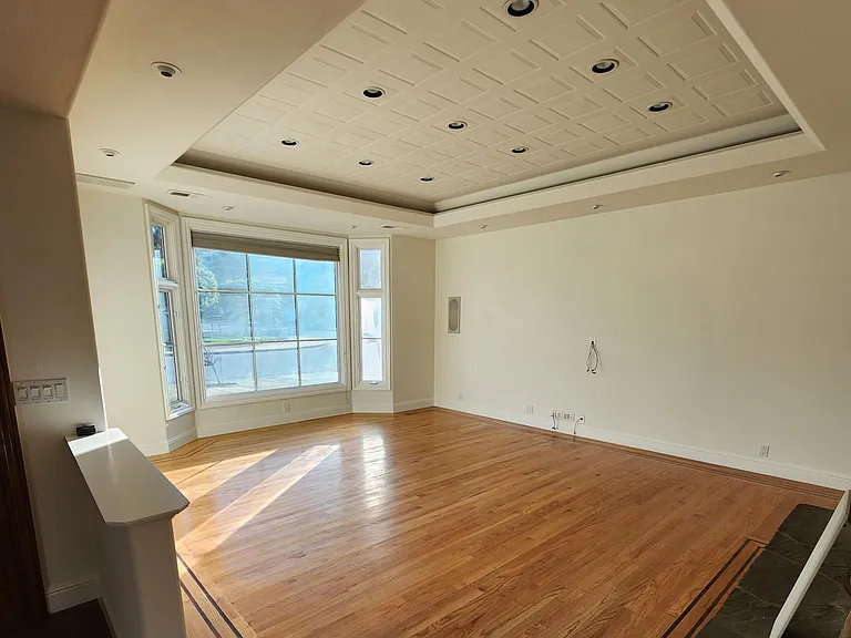 Family room with custom hardwood floors, coffered ceilings, river rock fireplace & high quality sound system.