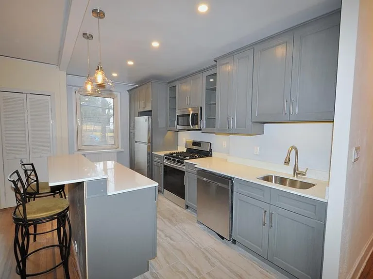 Renovated Kitchen with center Island, pendent lighting, Granite Counters, Stainless Steel Appliance including a dishwasher, range, microwave and refrigerator. The wall separating the eat-in-kitchen and living room have been removed and a center Island ins