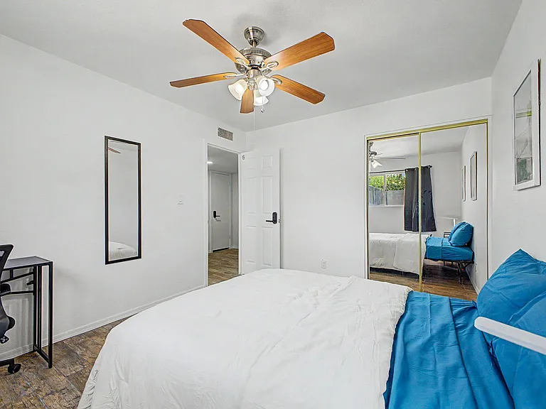 Private bedroom with a ceiling fan, mirrored closet doors, and space for a desk or reading chair.