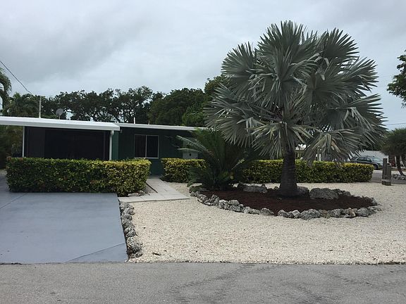Screen porch on left side of photo. Yard nicely landscaped.