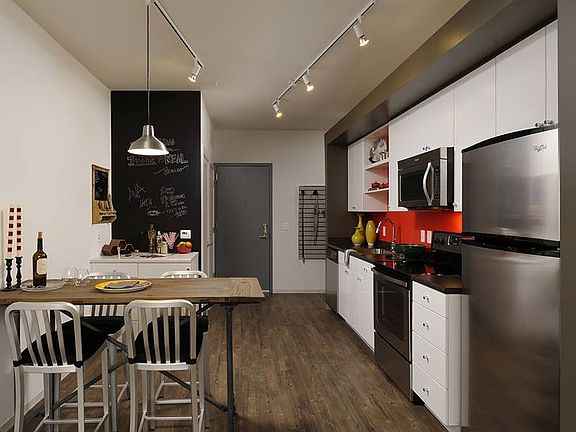 Kitchen with white cabinetry, black countertops, stainless steel appliances, chalkboard wall and hard surface flooring