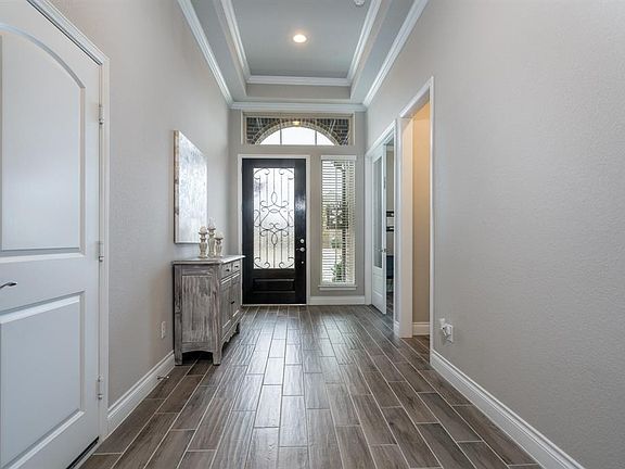 This view back towards the front of the home shows a double tray ceiling featuring crown molding, recessed lighting and the door surrounded by sidelights and a transom window! What an inviting space!