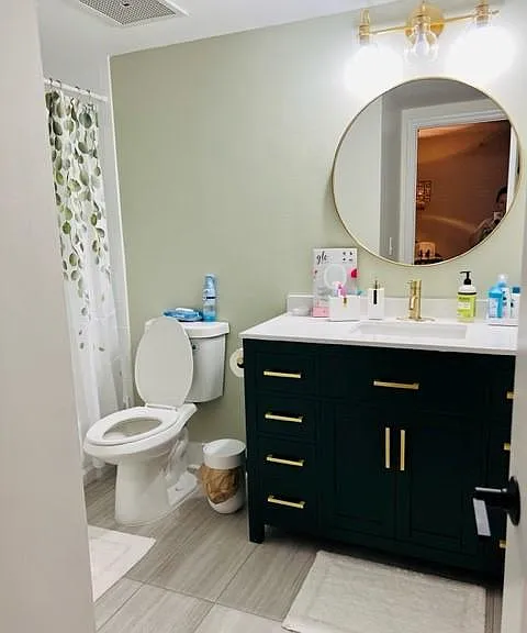 Bathroom with new flooring, new vanity, new mirror, new light fixture, new toilet and painted tile and tub.