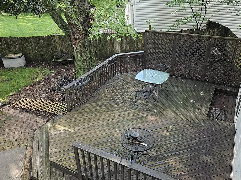 Big deck w/ two iron chairs, one glass top table, one iron table, a long water hose