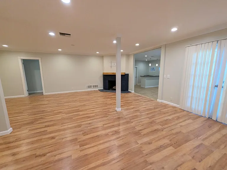 This wide-angle view shows the view from the dining area and living room. On the far left, you'll find a door that opens into a hallway for the bedrooms. On the right you'll see the bonus room and French doors that open to the back yard.