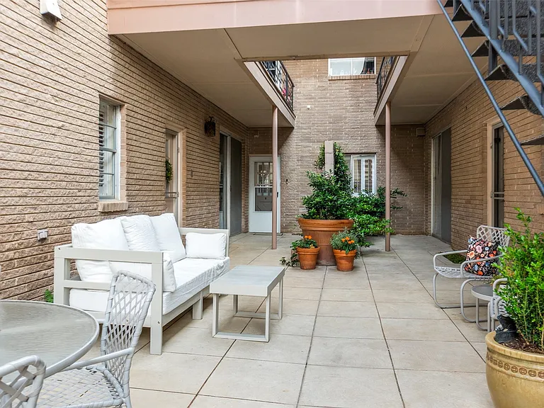 Courtyard patio featuring large format tile flooring, brick exterior walls, and a multi-level layout