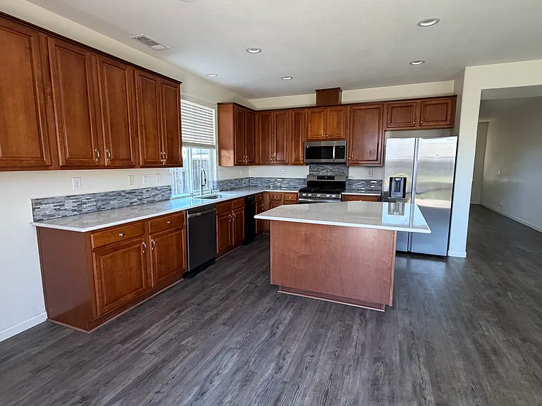 Kitchen, island, fridge, oven, microwave, dishwasher and stanlis steel sink.