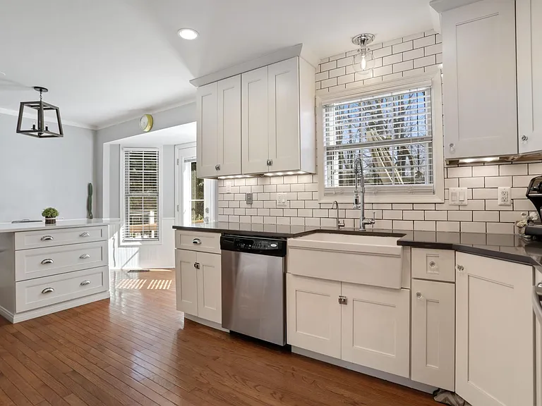 Beautifully remodeled kitchen with new dishwasher, new refrigerator, and new microwave range hood. Note the maple cabinets, farmer sink and quartz countertops.