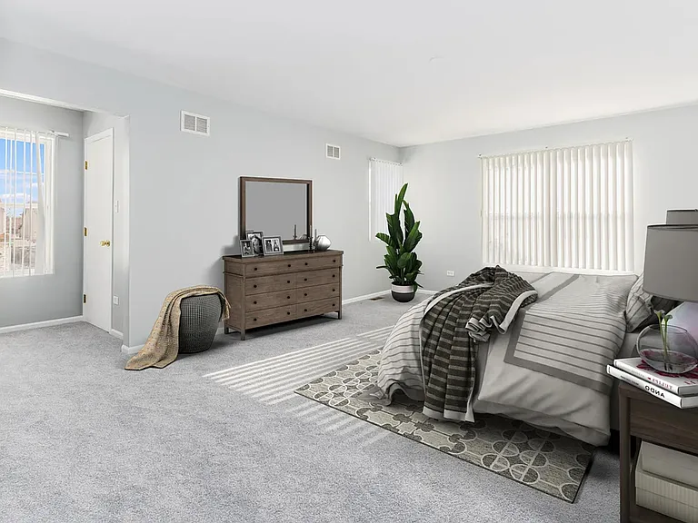 Spacious carpeted bedroom with large windows, vertical blinds, and ample room for a full bed plus dresser storage.