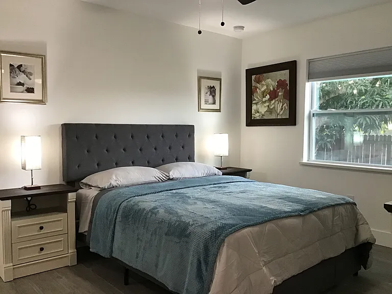 Spacious primary suite featuring dual nightstands and blackout shades designed for restful comfort.