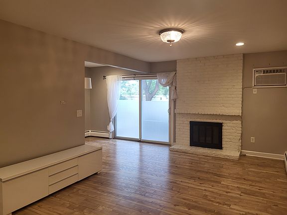 _ COZY & SPACIOUS LIVING ROOM: Connected to the dining and entrance area it features a decorative fireplace, modern recessed lighting, mini-chandelier, and an AC wall unit. Open-concept layout with easy-to-clean LVP flooring! _____