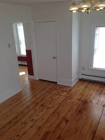 Living room looking towards kitchen, which has been painted all white.