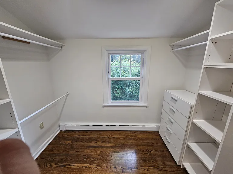 First-Floor Bedroom 2
Walk-In Closet with built-in shelving, hanging space, drawers, hardwood floors, and a window for natural light.