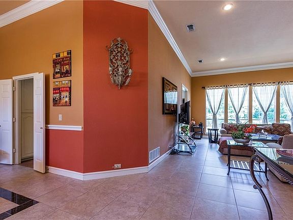 As you enter this home the formal dining room is on the left and you see the family room.  The wall of windows look out on the pool and the landscaped backyard.   The doors on the left lead to the kitchen.  Ceramic tile floors and crown molding.