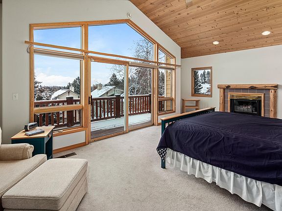Large Primary bedroom with fireplace and deck with a view of the mountains.