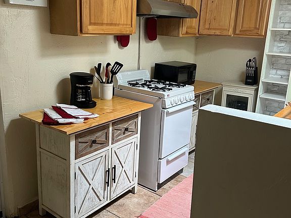 Kitchen with gas range, microwave and coffeepot.
