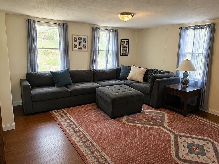 This good sized living room space will accomodate a regular size sectional. Built-in bookcase w/storage is on one wall. (AI Generated for Scale.)