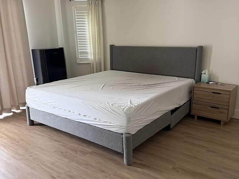 Furnished bedroom with a platform bed, nightstand, ceiling fan, and window with blinds and curtains.