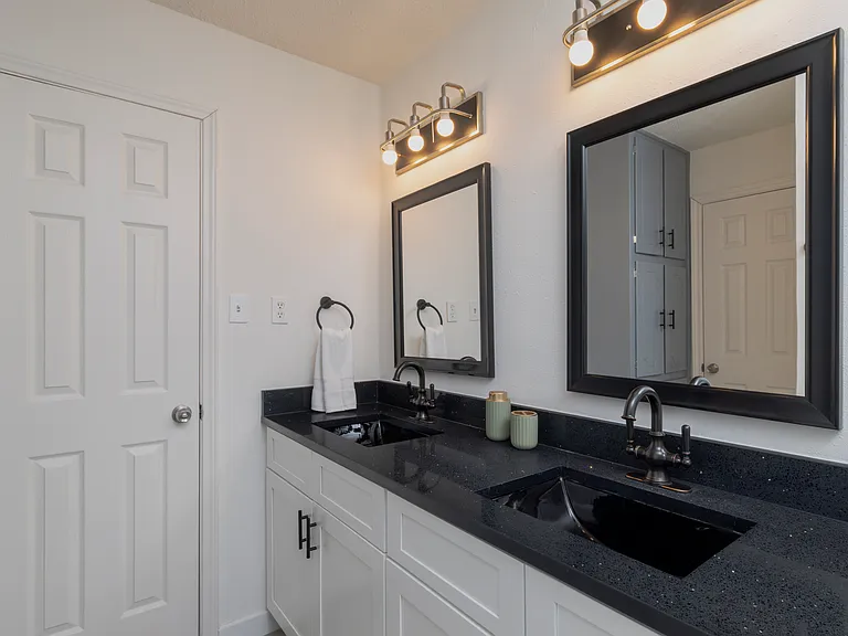Full bathroom with double sinks and shower-tub combo attached to bedroom 1.