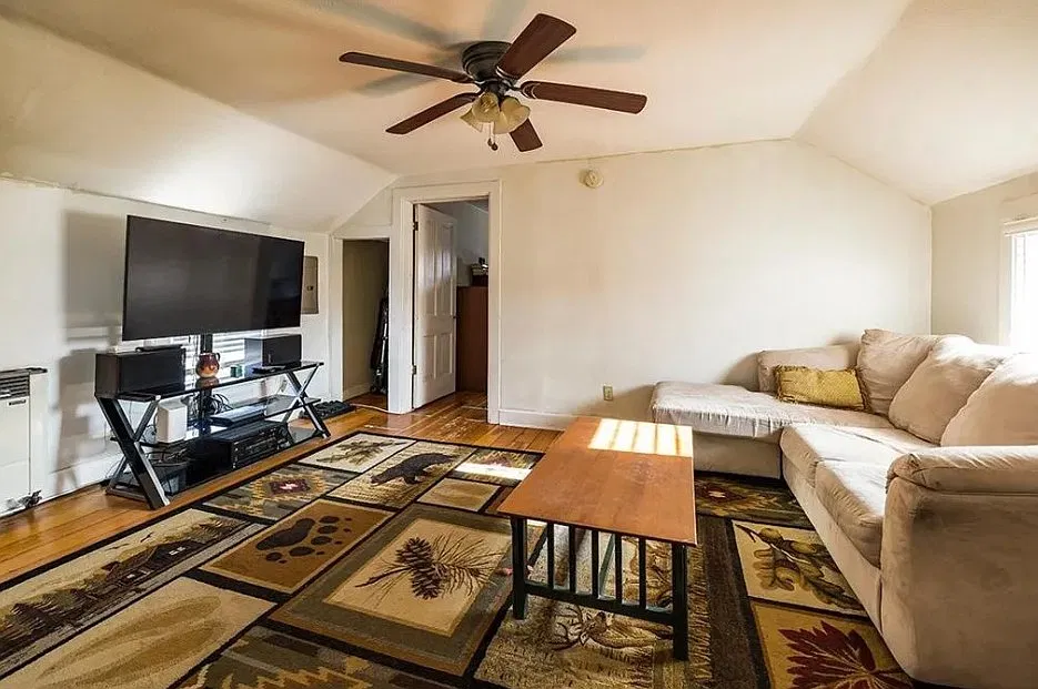 Living room with ceiling fan and orginal hardwood floors throughout.