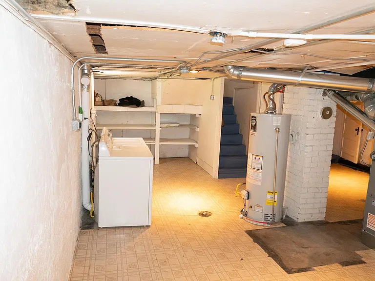 Basement Southside with washer and dryer. Storage shelves in the background and the stairway is just the right of the shelves.