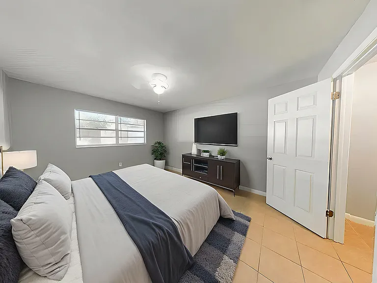 Inviting bedroom with a plush bed, sleek modern furniture, and a large window for natural light.
