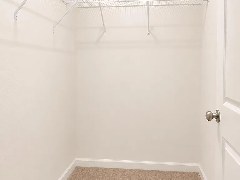 Spacious walk-in closet with wire shelving on two sides for convenient hanging and storage.