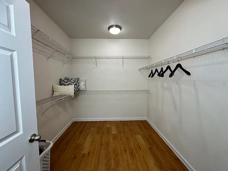 Spacious walk-in closet with elegant composite wood flooring, organized shelves, and ample hanging space. Spacious walk-in closet with elegant composite wood flooring, organized shelves, and ample hanging space.