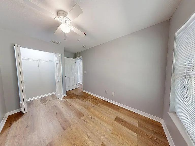 Bright and cozy bedroom with elegant wooden flooring, a spacious closet, and large windows offering ample natural light.