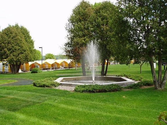 There are flower gardens, mature trees and a fountain.