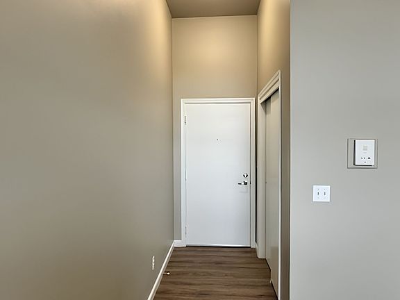 Inviting apartment entrance with high ceilings and modern neutral tones, featuring sleek wooden flooring for a warm welcome. Inviting apartment entrance with high ceilings and modern neutral tones, featuring sleek wooden flooring for a warm welcome.