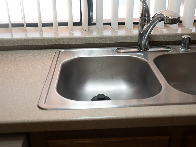 Stainless steel sink with reverse osmosis. Window looks out toward pool.