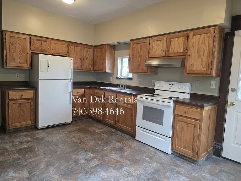 Kitchen with Amish made cabinets, range/stove and fridge.