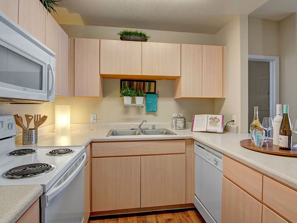 A kitchen with light cabinets and white appliances