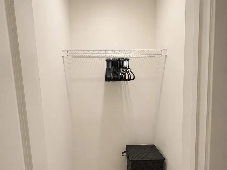 Dedicated closet with a wire shelf and hanging rod, plus floor space for bins or luggage storage.