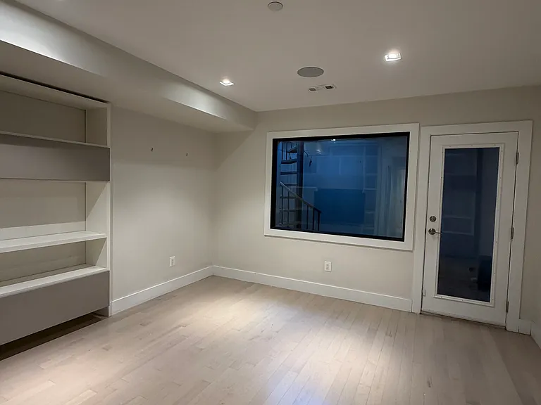 The primary bedroom has ample space for a king bed and end tables on either side. The combination of custom open and closed shelves provides generous storage for books and clothing.